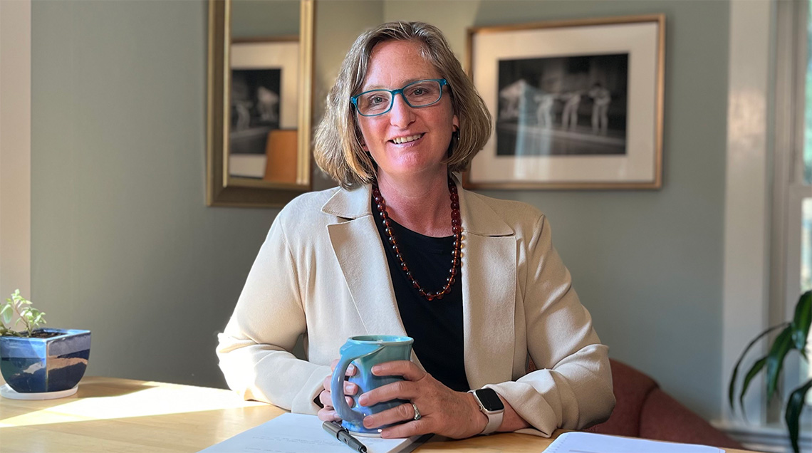 Sherry at her desk smiling while holding a mug